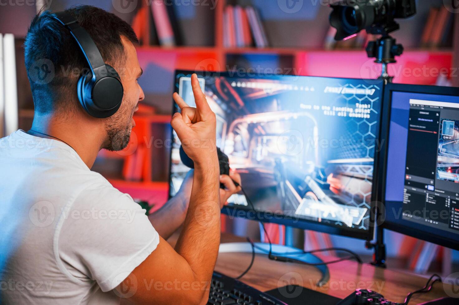 Male game streamer in casual clothes, is indoors with pc photo