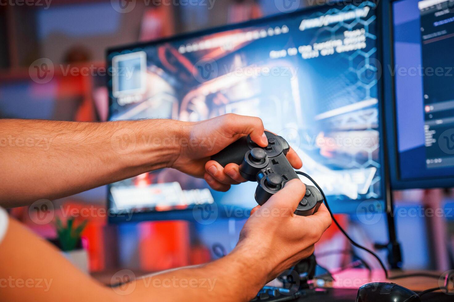 Close up ,view of hands with joystick controller. Male game streamer in casual clothes is indoors with pc photo