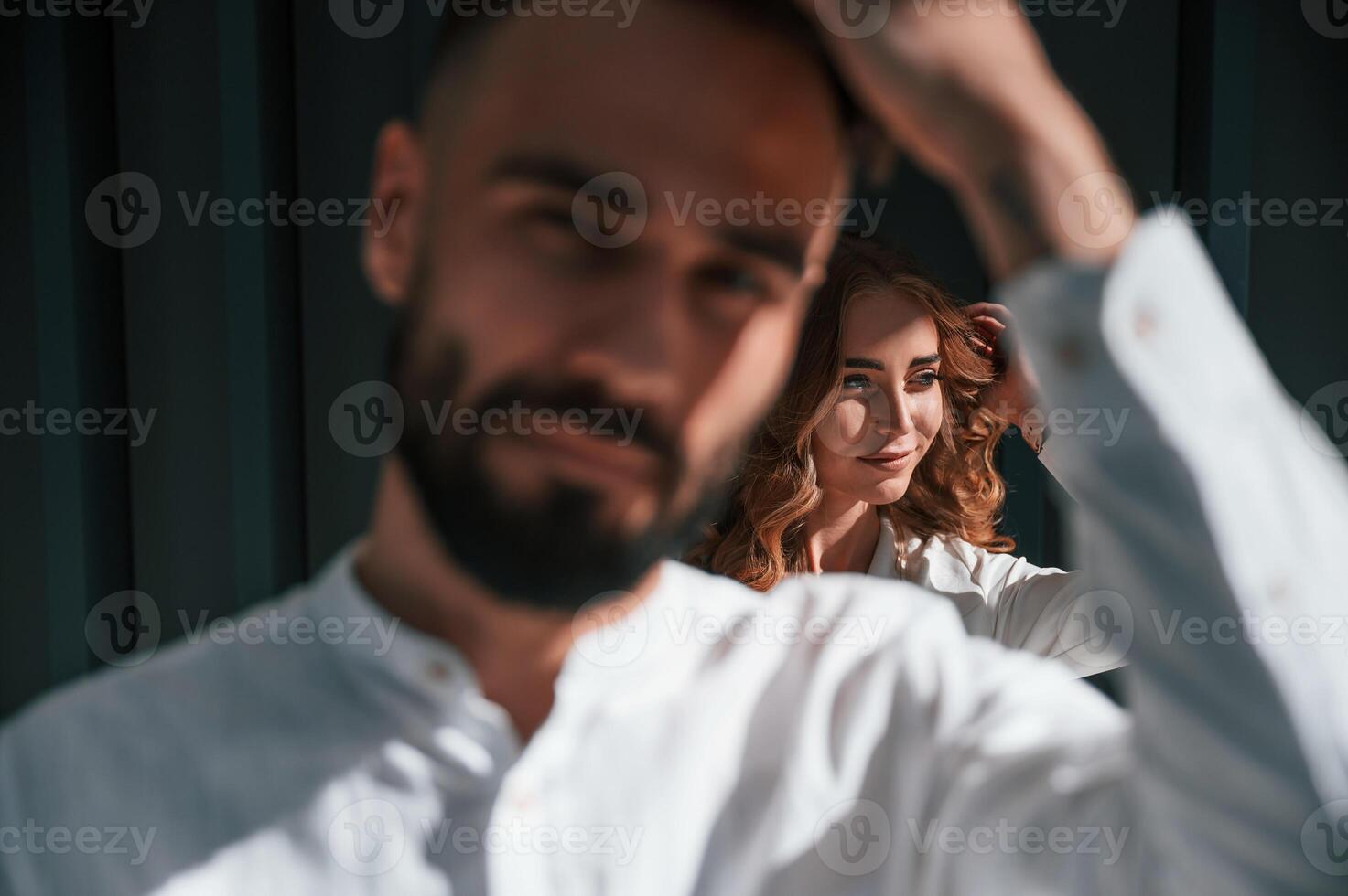 Beautiful young couple is standing together against dark green background photo
