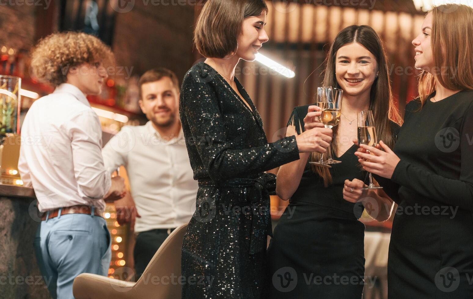 Having fun. Group ,of people, in beautiful elegant clothes are celebrating New Year indoors together photo