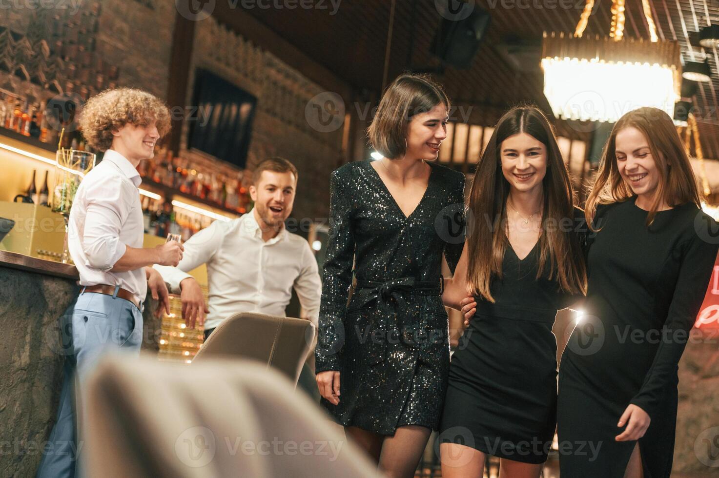 Man, is looking at the back of woman. Group of people in beautiful elegant clothes are celebrating New Year photo