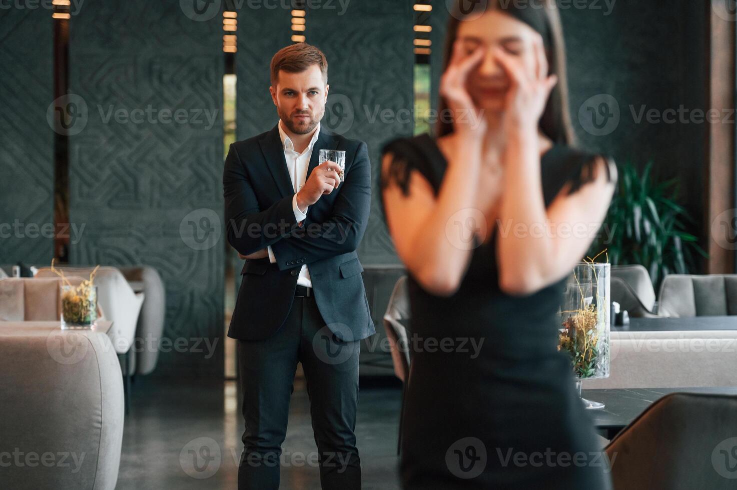 Man in black suit is angry at woman that is standing and crying photo