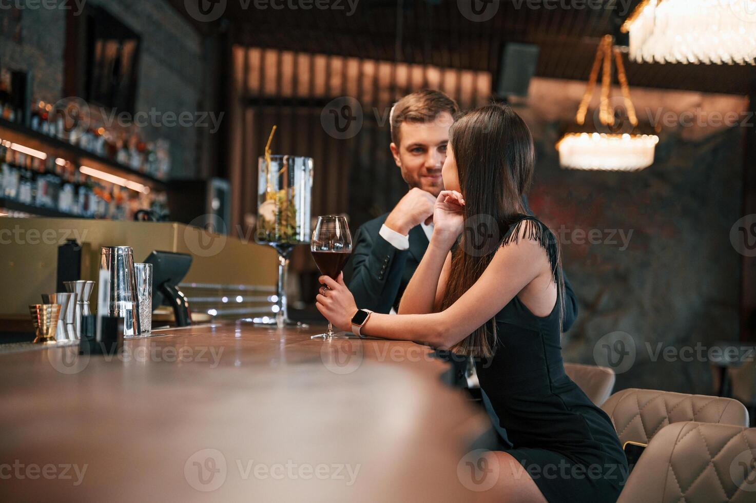 Side view,. Man and woman are sitting at the bar with alcohol drink photo