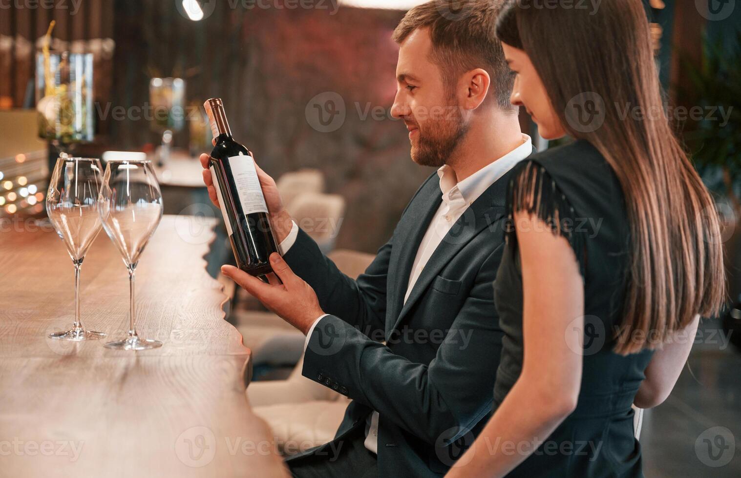 With wine bottle. Man and woman ,are sitting at the bar with alcohol drink photo