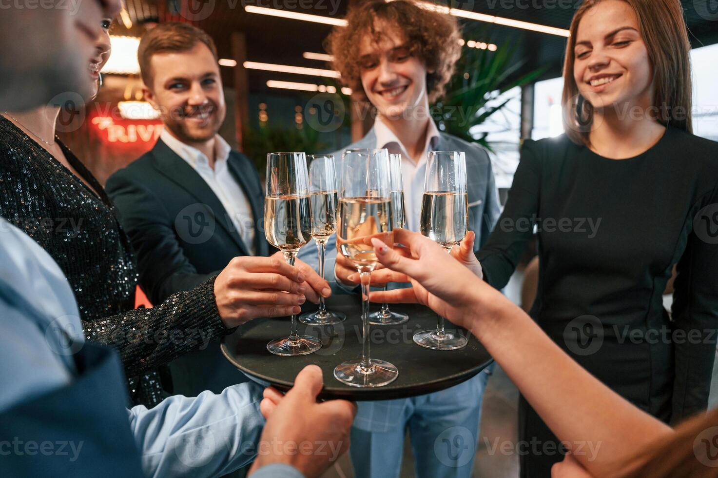 Taking glasses with champagne.. Group of people in beautiful elegant clothes are celebrating New Year indoors together photo