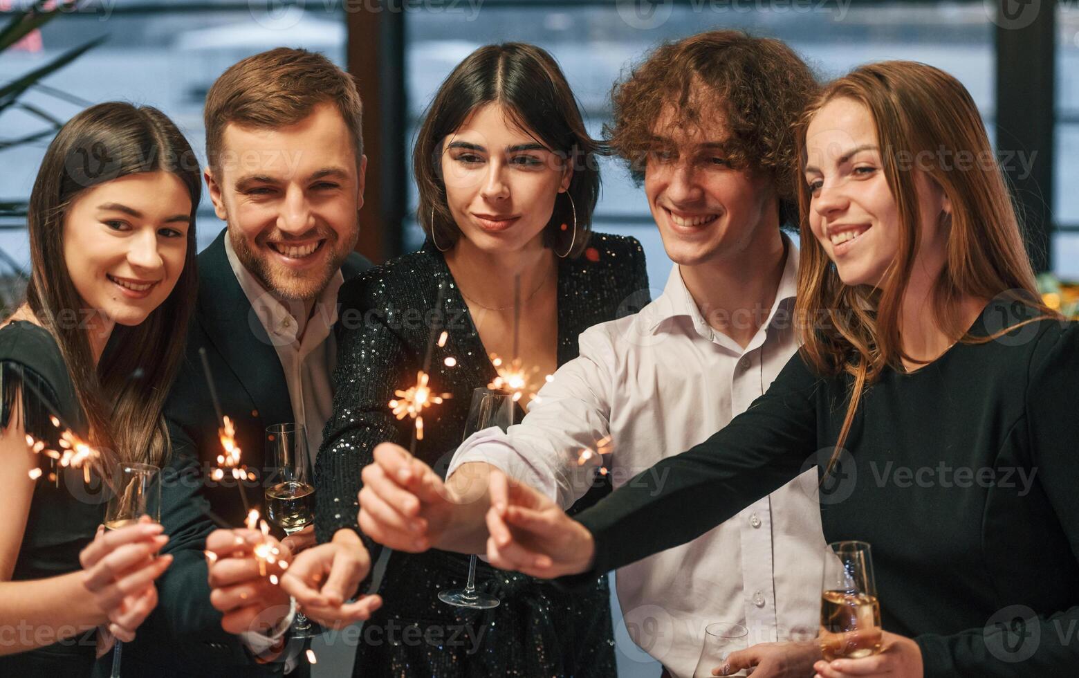 With new ,year sparklers. Group of people in beautiful elegant clothes are indoors together photo