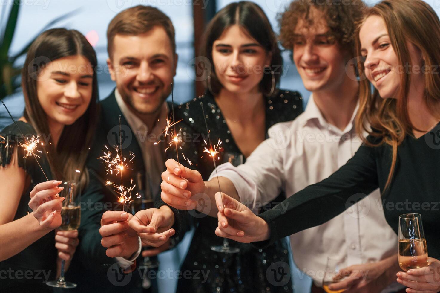 With new year sparklers.. Group of people in beautiful elegant clothes are indoors together photo
