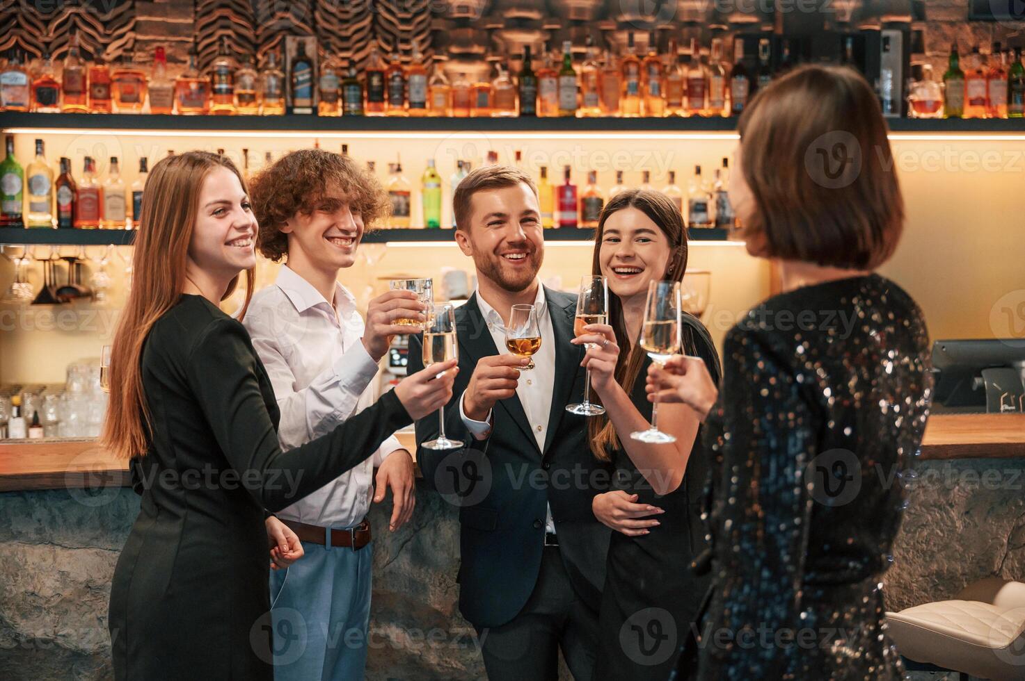 Talking, smiling, having fun. Group ,of people in beautiful elegant clothes are celebrating New Year indoors together photo
