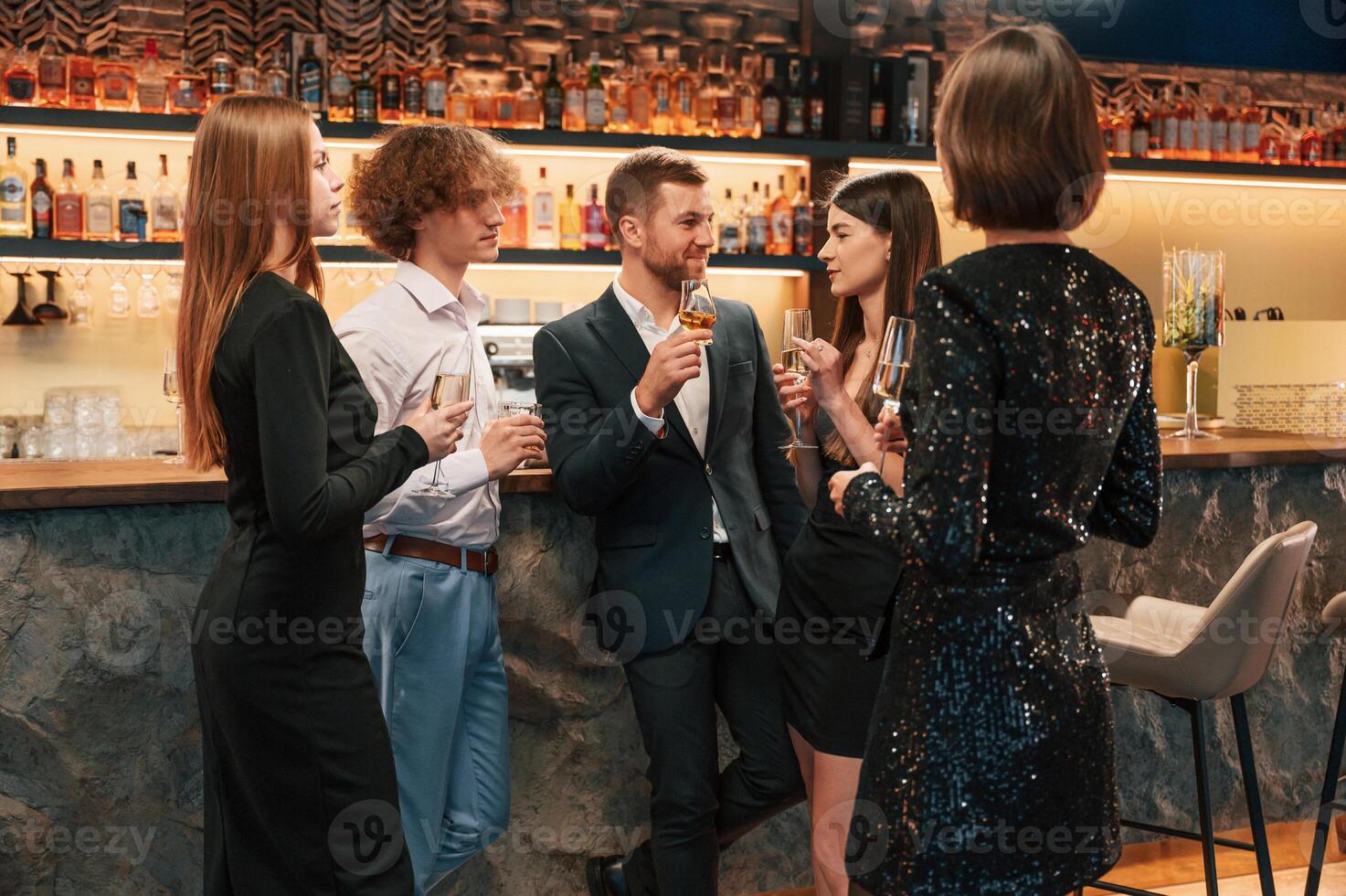 Talking, smiling, having fun. Group of people in beautiful elegant clothes are celebrating New Year indoors together. photo
