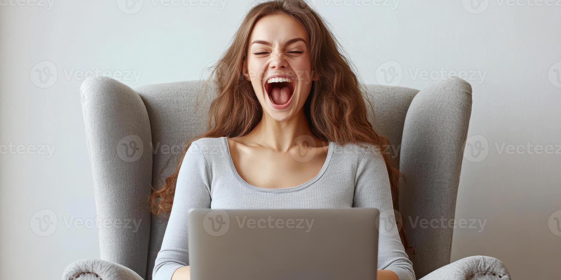 Young woman expresses excitement while using a laptop in a cozy living room setting during daytime photo