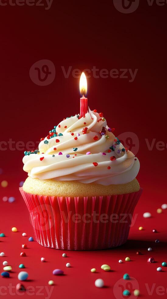 Colorful cupcake with a candle and sprinkles on a vibrant red background during a celebration photo
