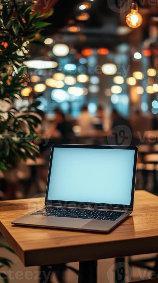 Laptop on wooden table in a cozy cafe with ambient lighting during a busy afternoon photo