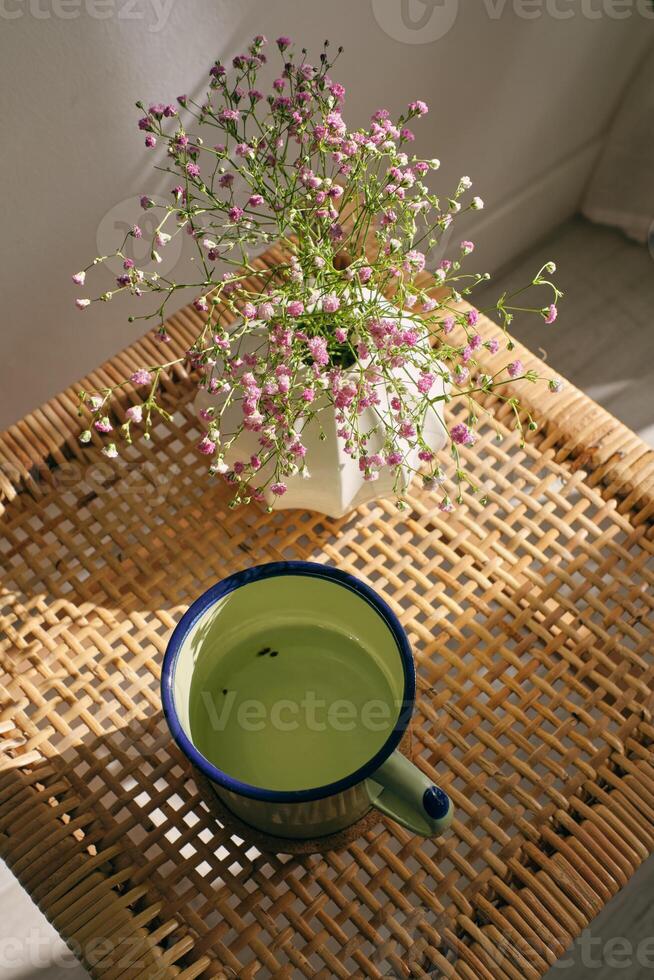 Cup of tea and blooming gypsophila on wicker table photo