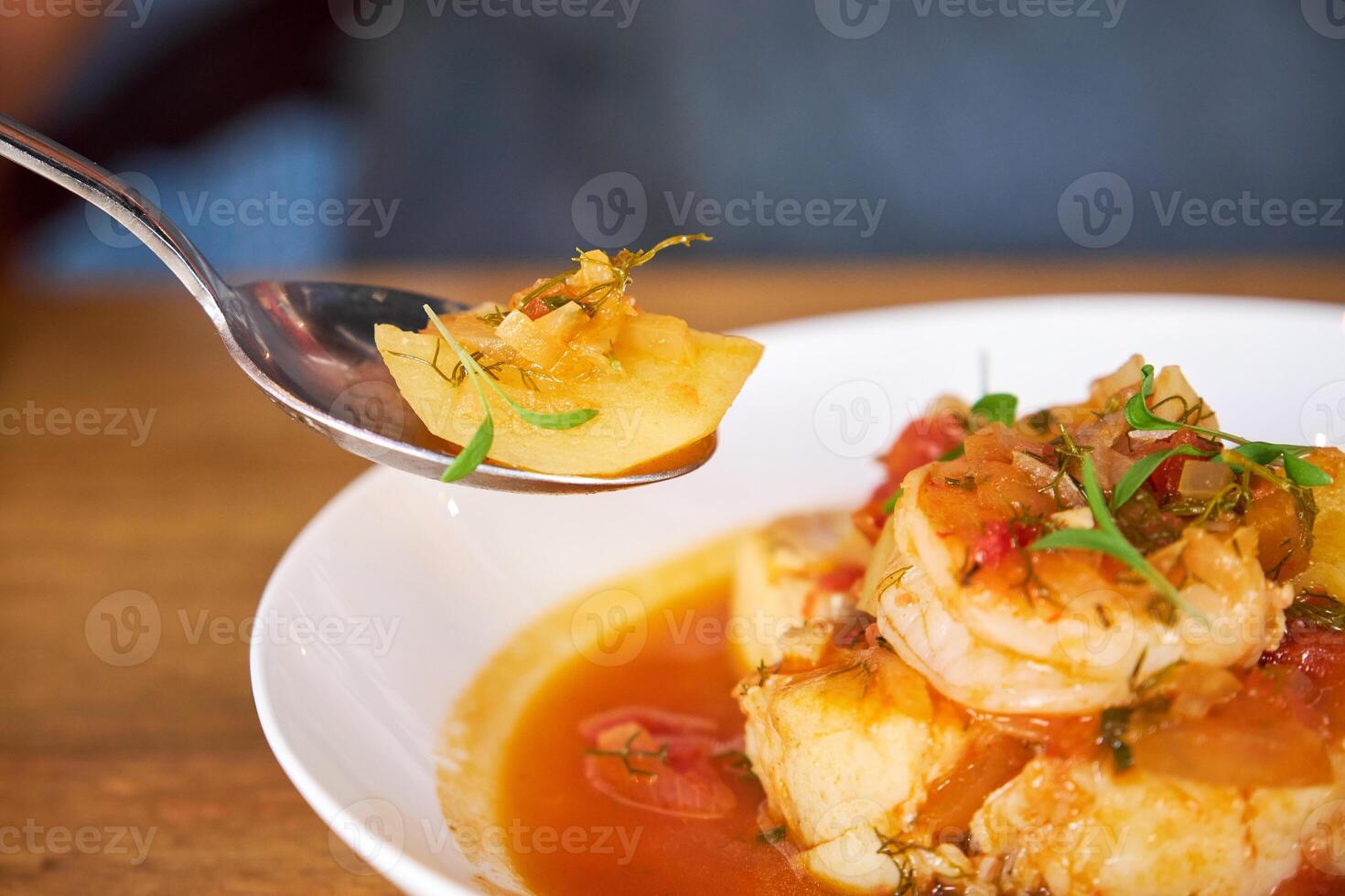 Selective focus on a spoon with a piece of potato from a cassero photo