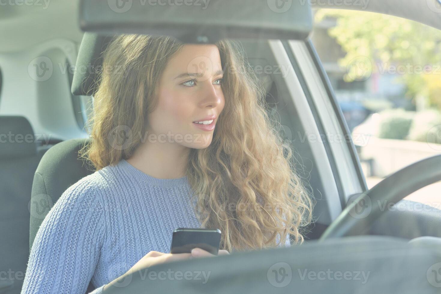 Beautiful woman using smartphone in car photo