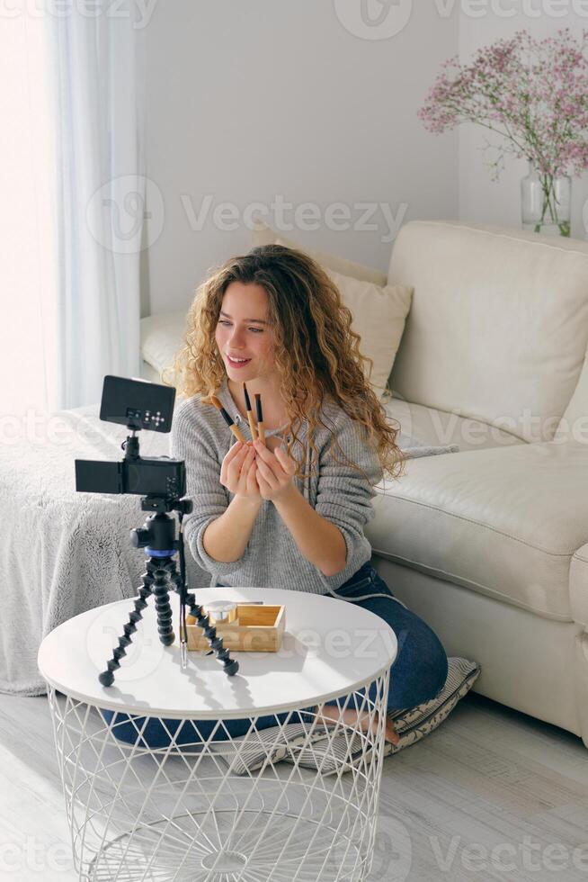 Woman live streaming and showing makeup brushes to followers photo