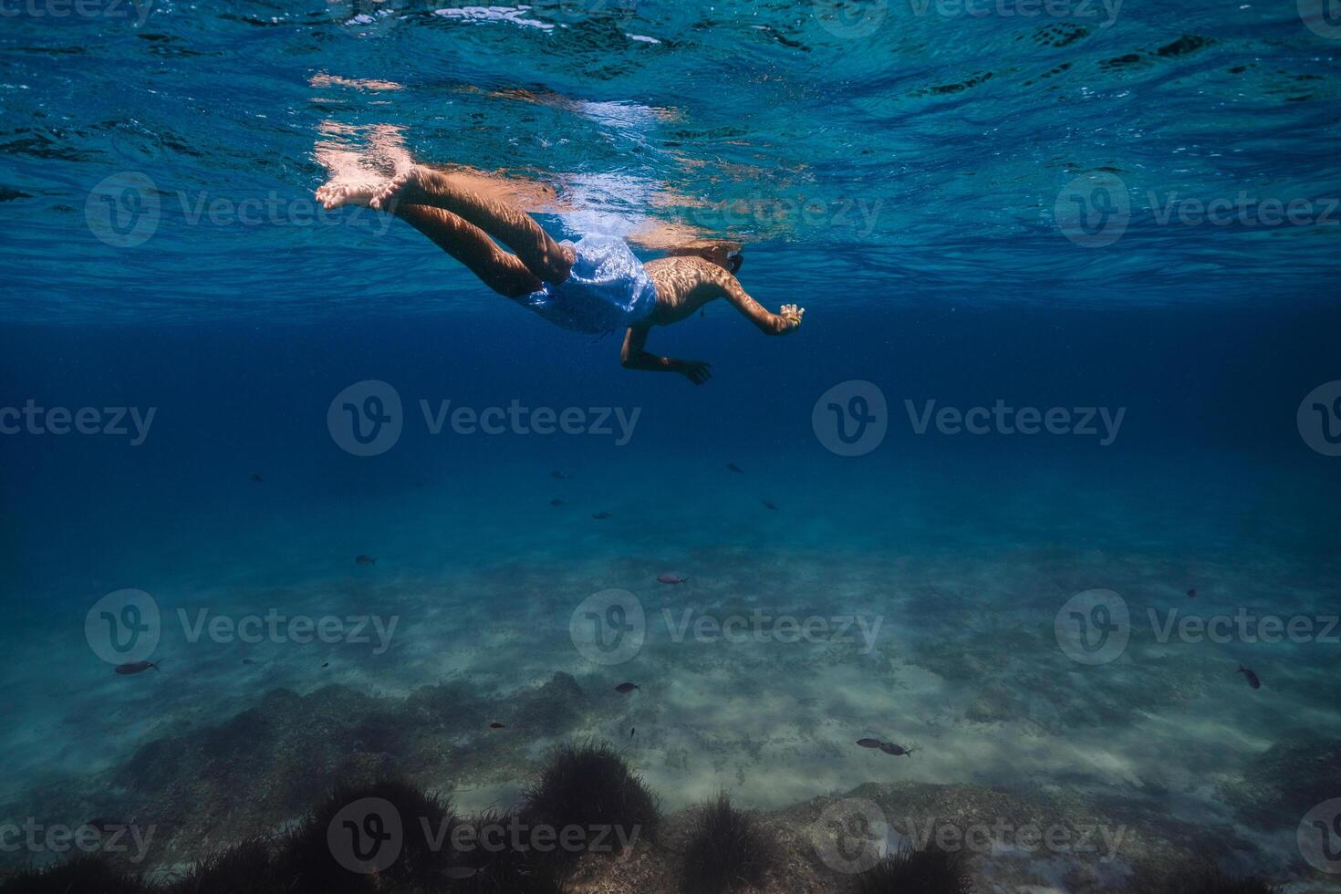 Unrecognizable kid snorkeling in blue sea photo