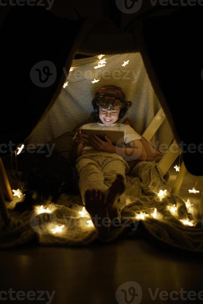 Cheerful boy watching in blanket fort photo