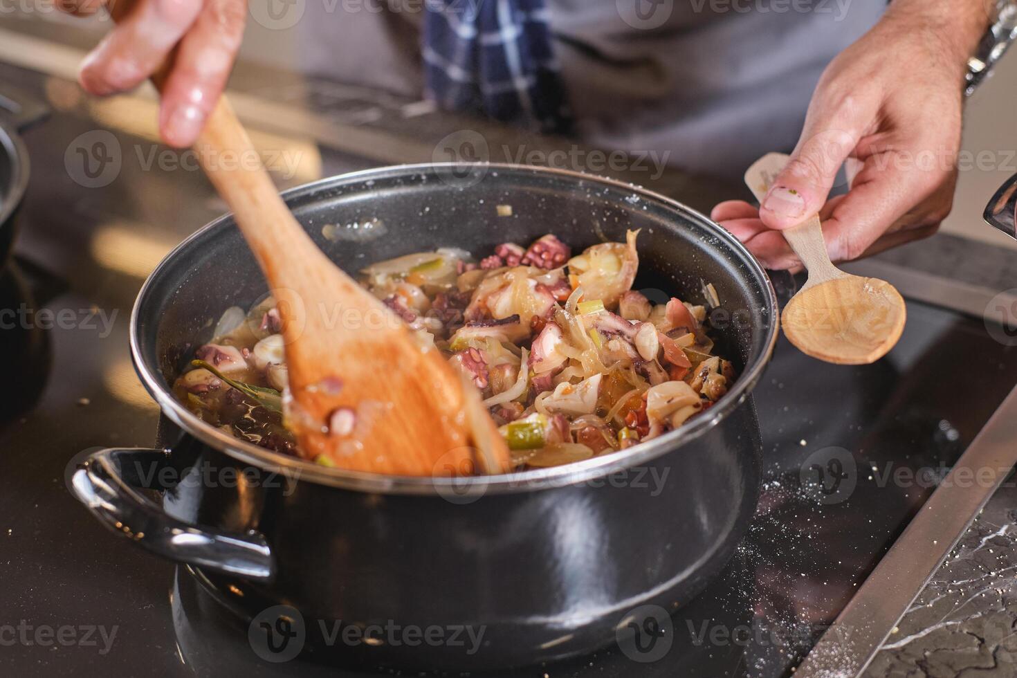 Crop man cooking food in saucepan in kitchen photo