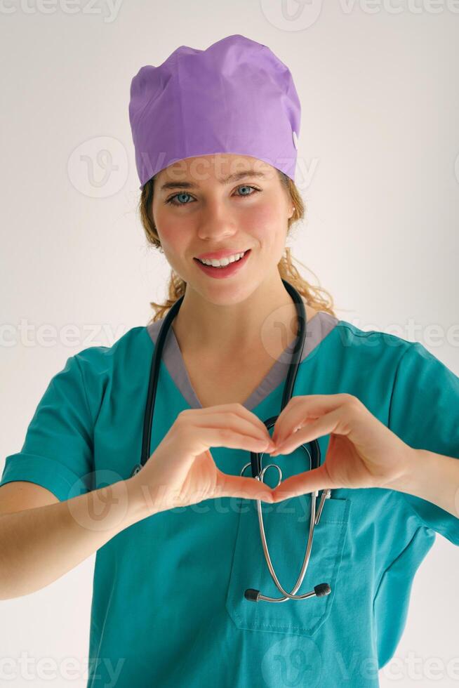 Cheerful medical worker making heart gesture on gray backdrop photo