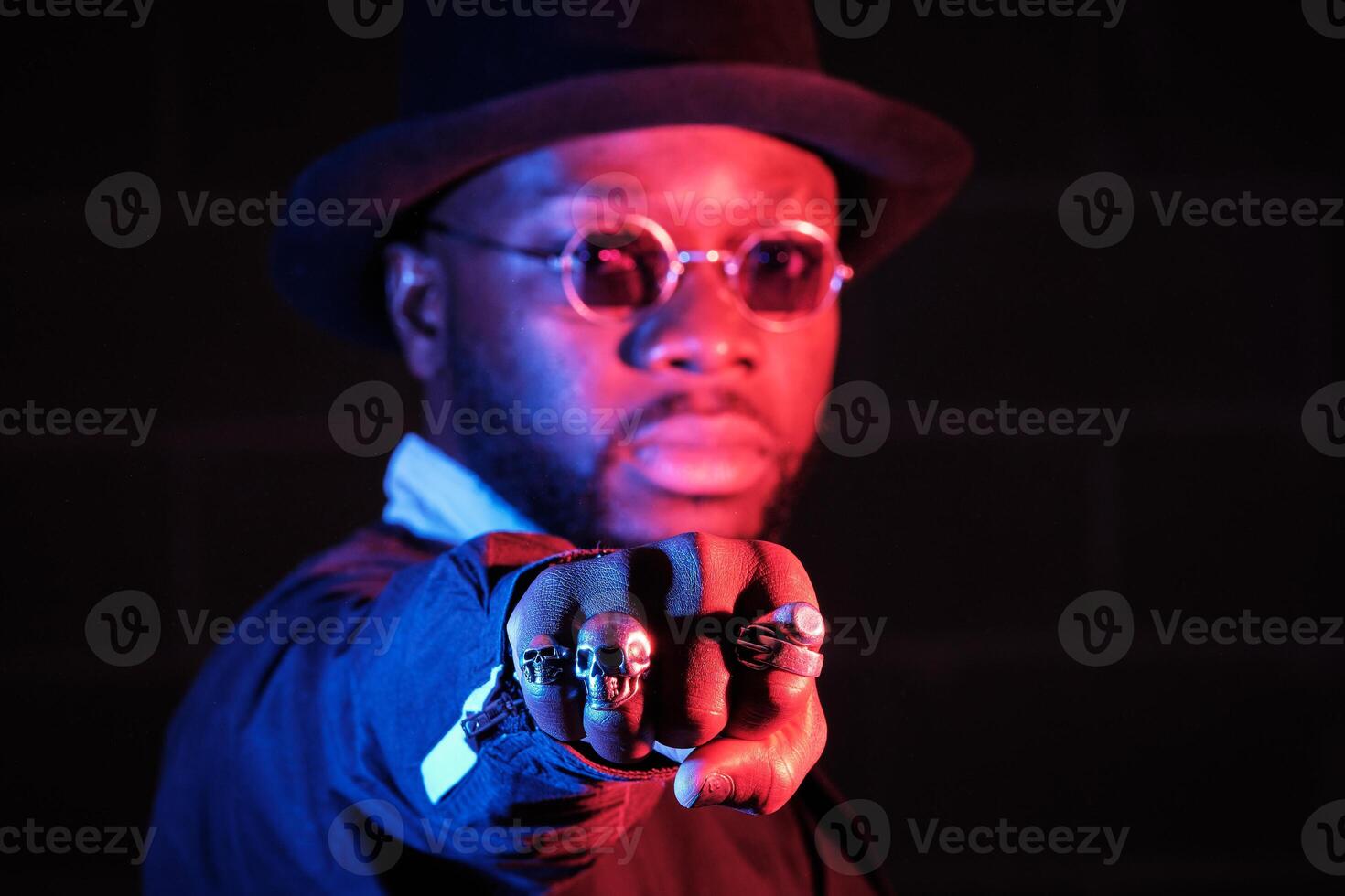 Stylish black guy in sunglasses showing fist in studio photo
