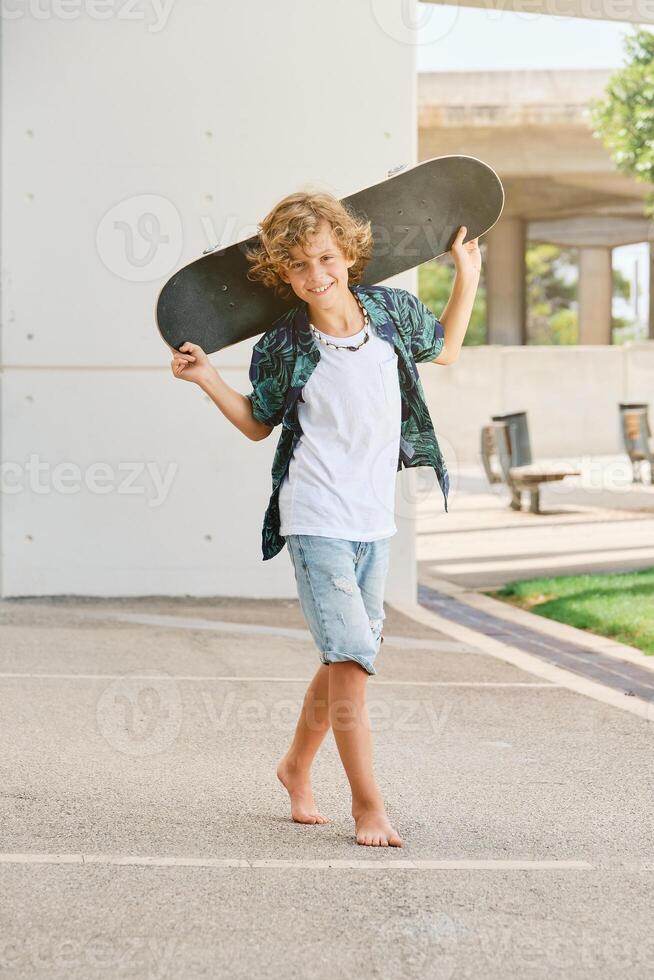 Barefoot boy with skateboard on street photo