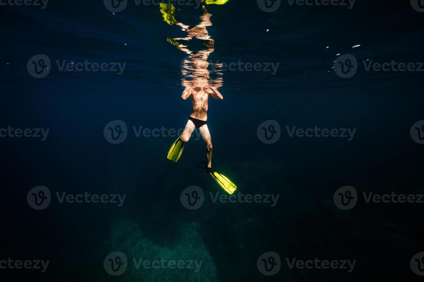 Anonymous fit man swimming undersea in sunlight photo