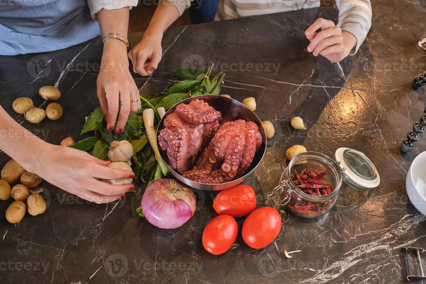 Faceless couple cooking at table with raw octopus photo
