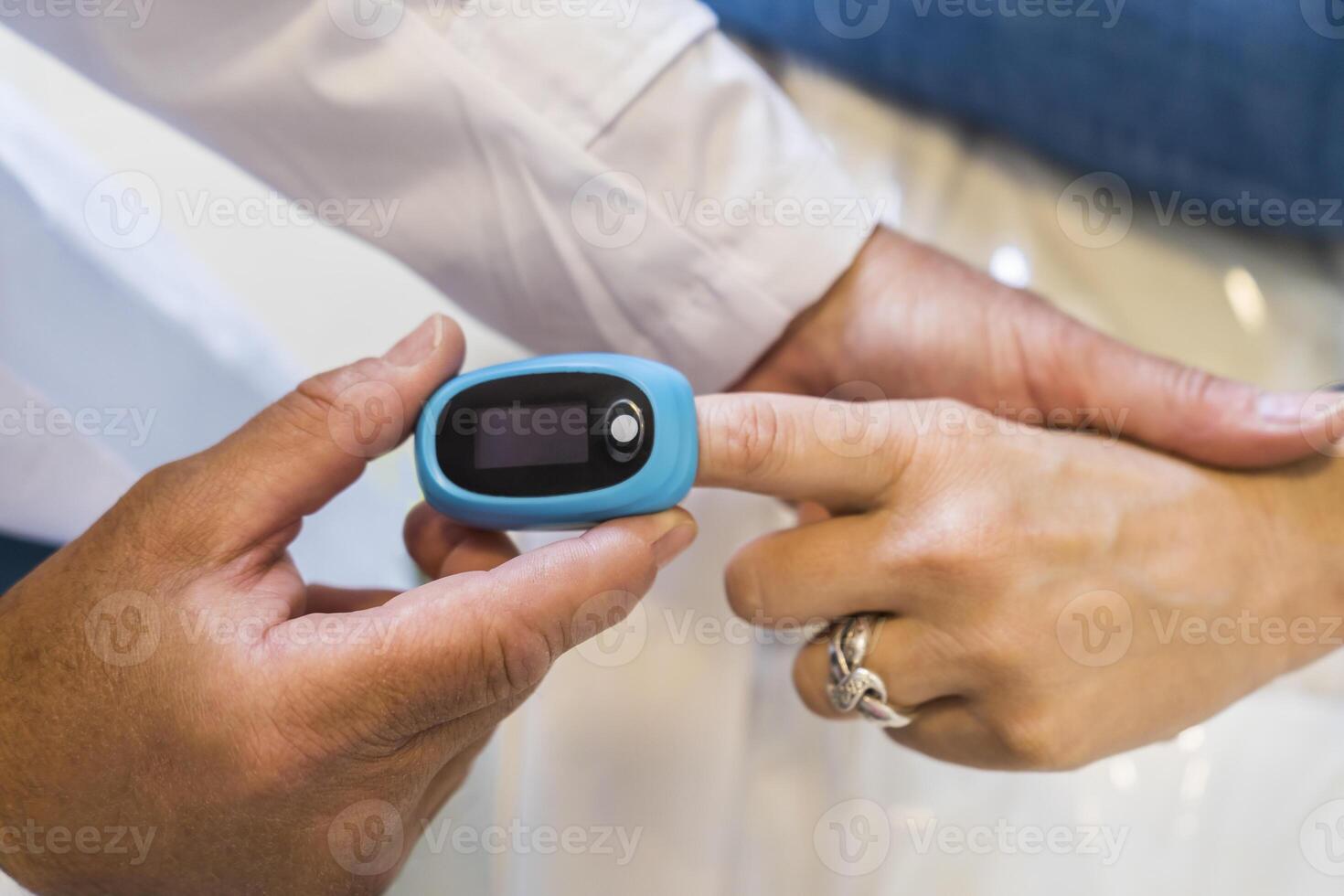 Doctor is putting a pulse oximeter in his patient's hand for measuring oxygen saturation in blood and heart rate. photo