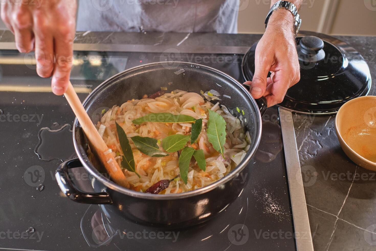 Unrecognizable man standing at stove in process of cooking photo