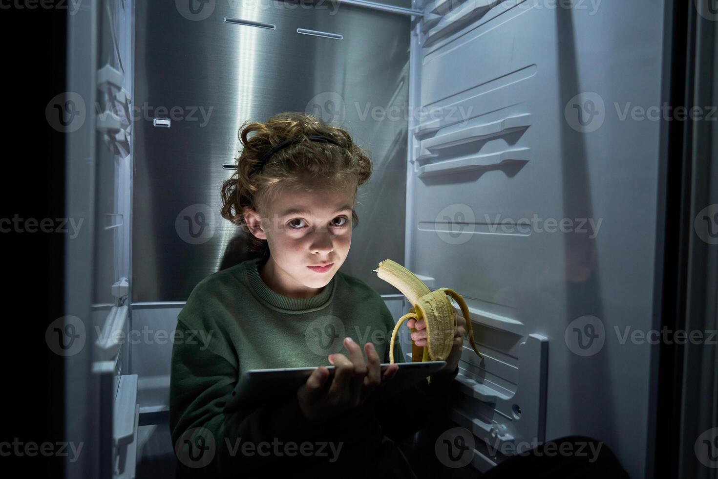 Boy with tablet sitting in fridge photo