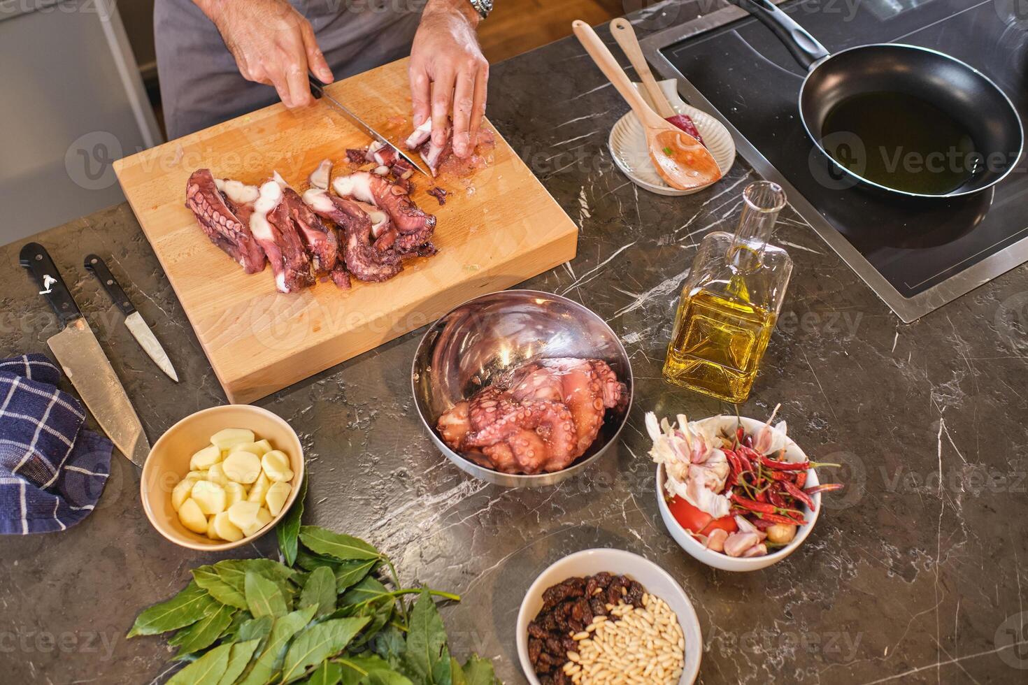 Unrecognizable person cutting octopus on kitchen table photo