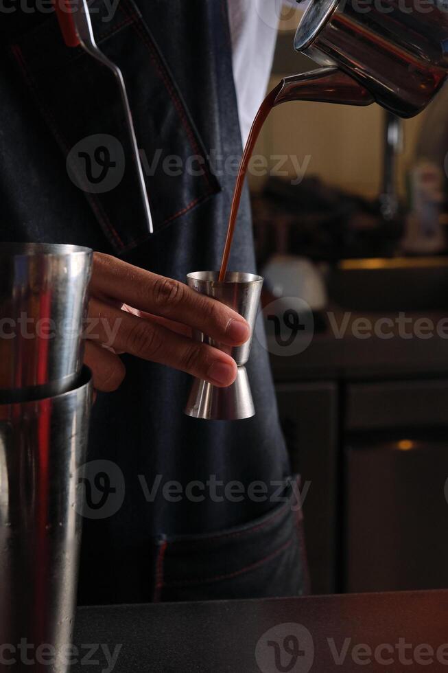 Crop bartender pouring coffee from kettle into jigger photo