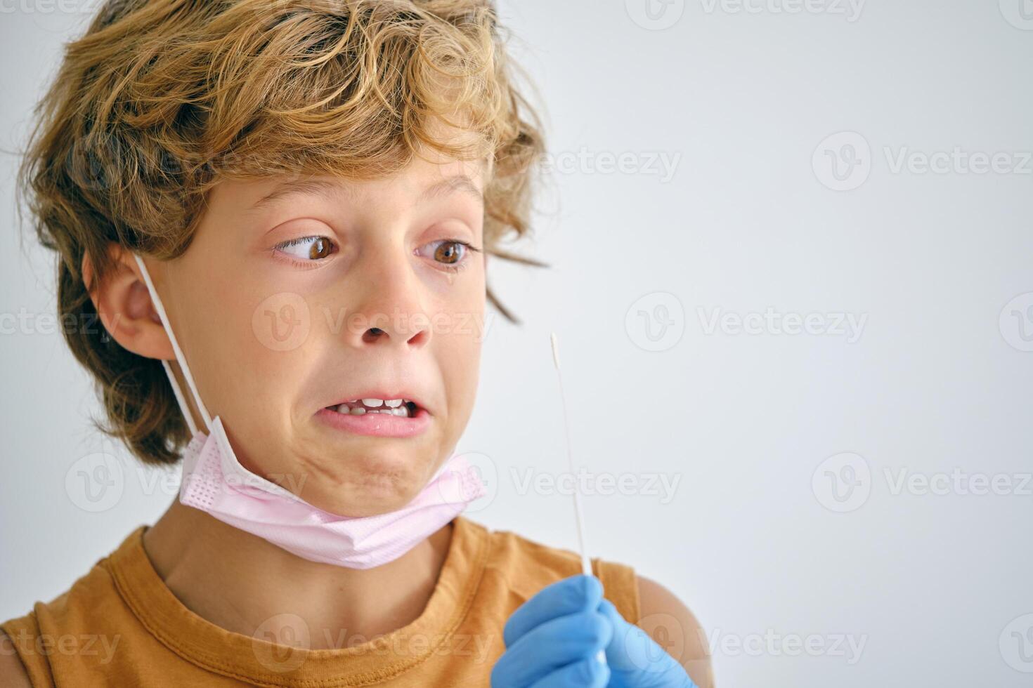 Scared boy with crop nurse during COVID test in clinic photo