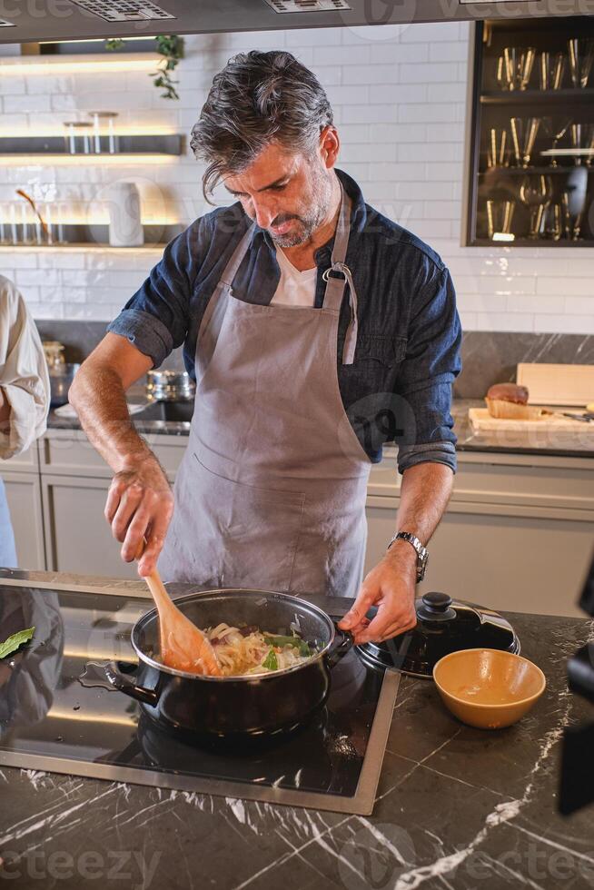 Adult man cooking dinner in kitchen photo