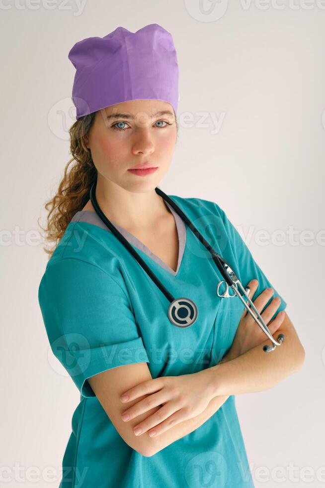 Lady in medical workwear with stethoscope against gray backdrop photo