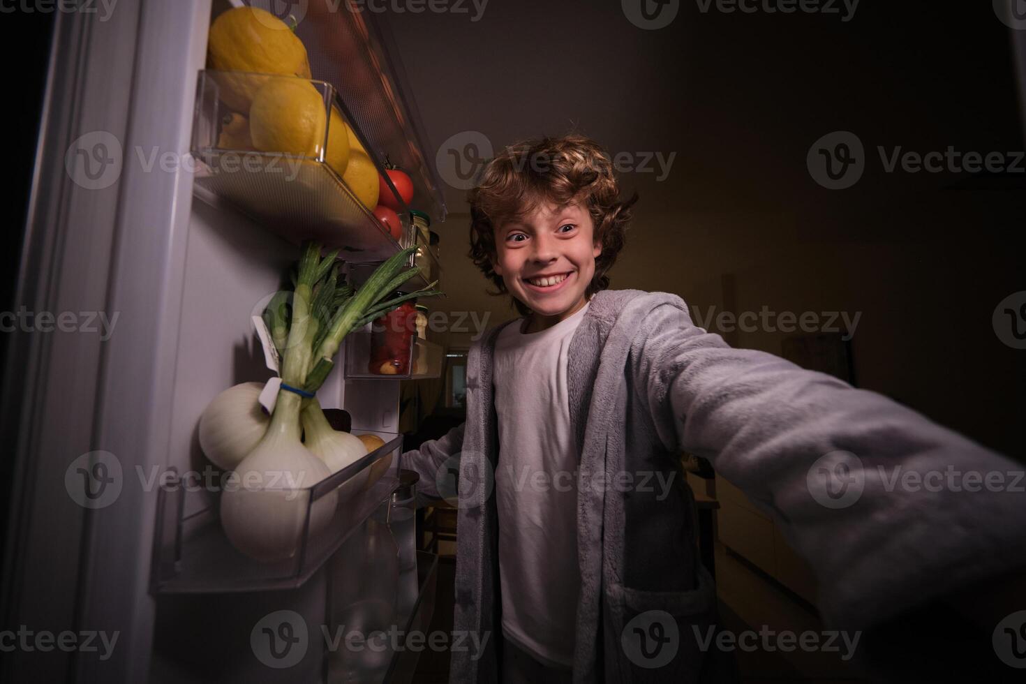 Joyful boy standing near opened fridge photo