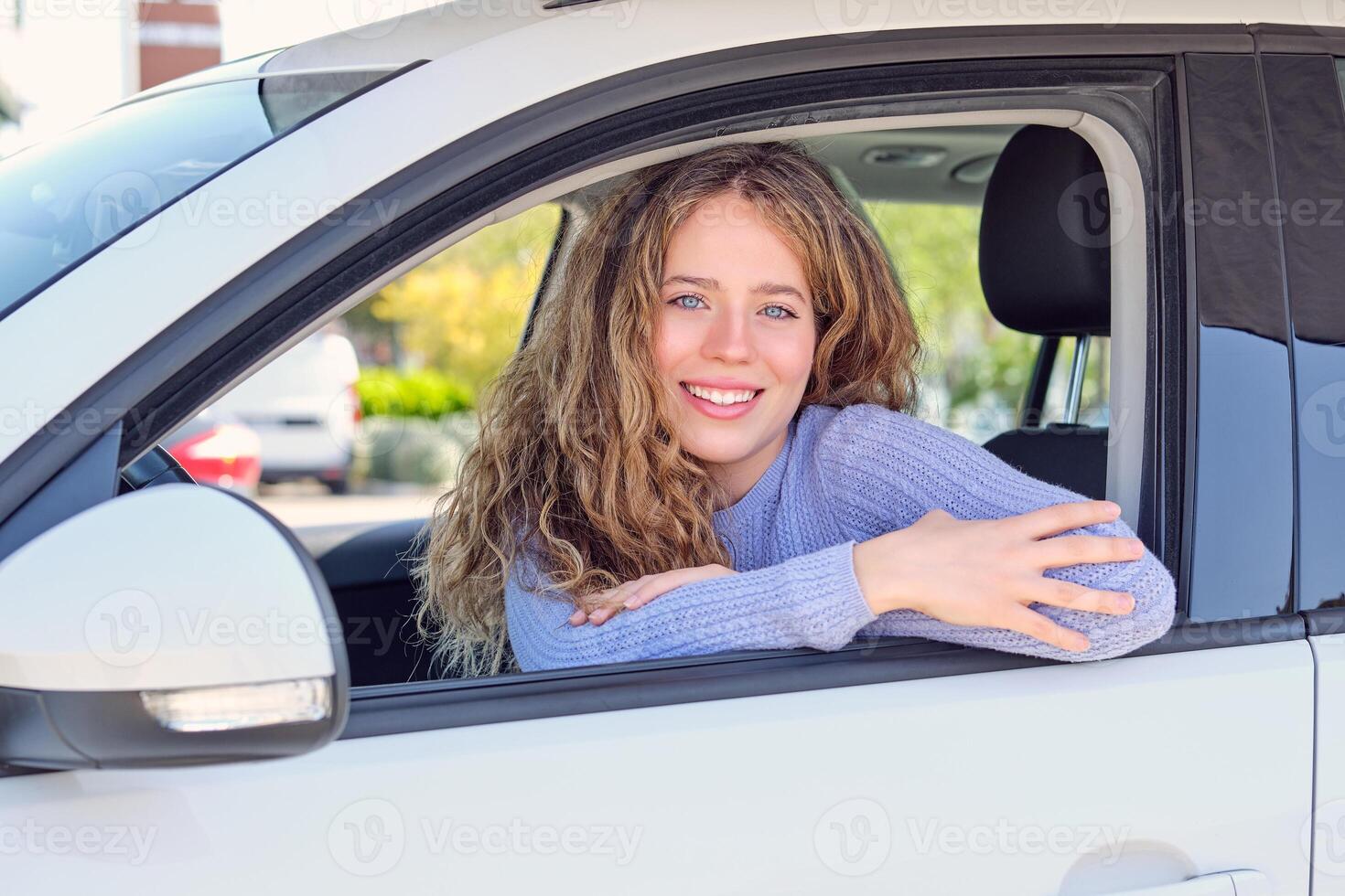 Gorgeous smiling woman sitting in car on sunny street photo