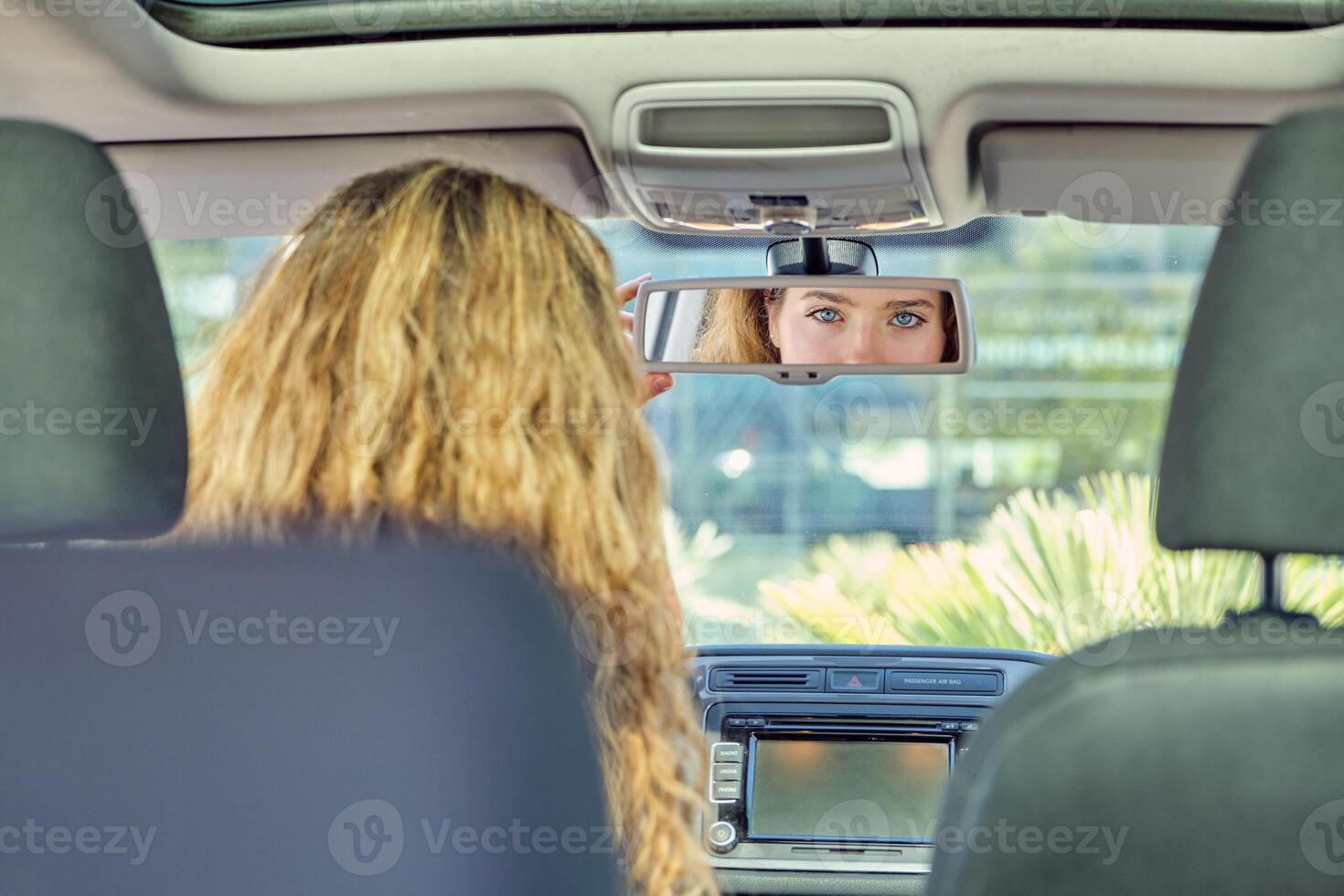 Beautiful woman in car looking in rearview mirror photo