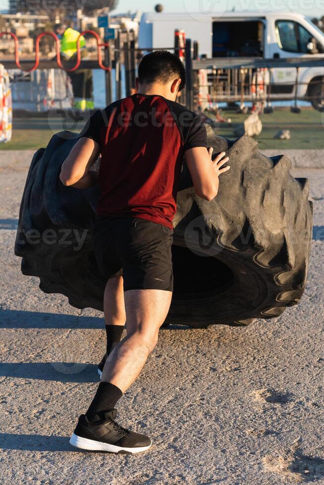 Strong man doing tire flip exercise at the park photo