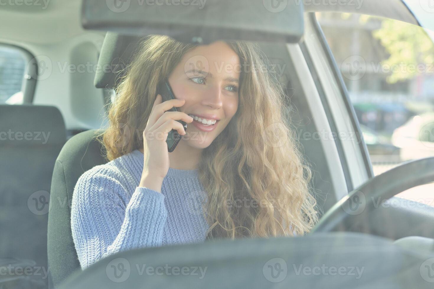 Smiling woman talking on smartphone in car photo