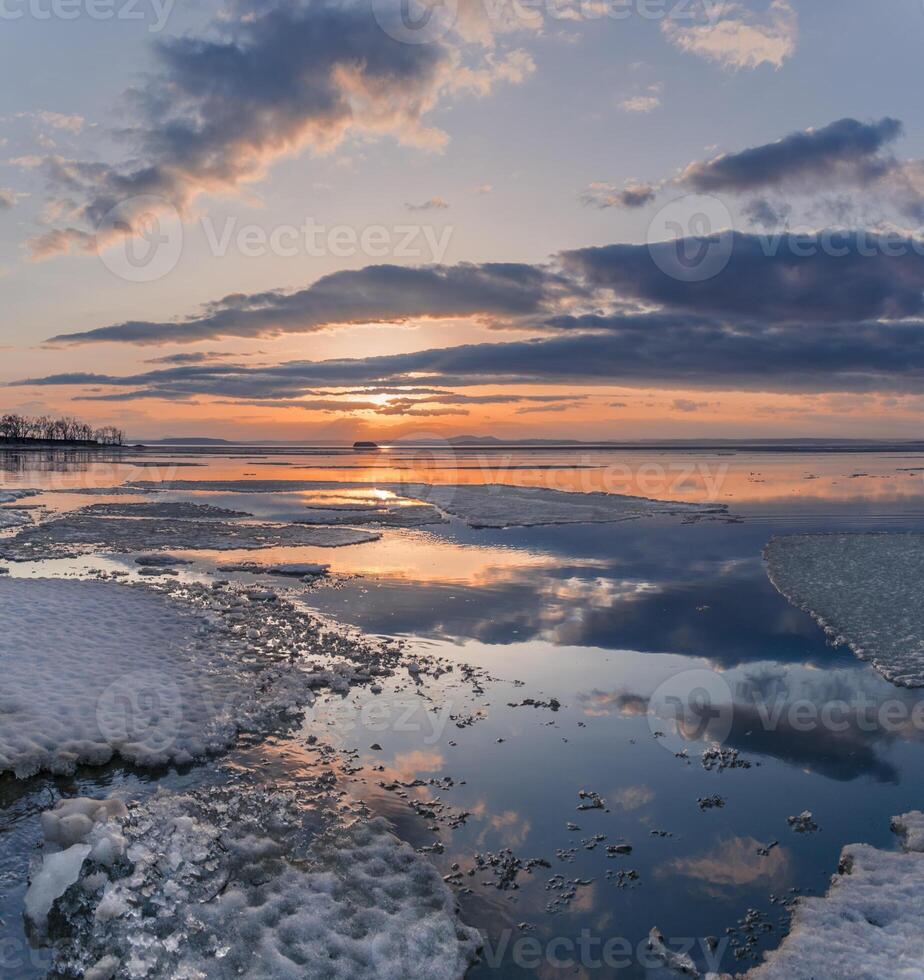 Winter. The surface of the ice is bound by ice, with a perfectly smooth, mirror-like appearance. Sunset in winter over the lake. photo