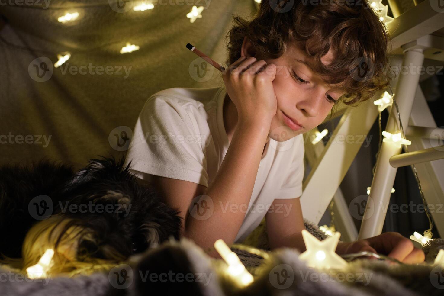 Content boy with pencil in blanket fort photo