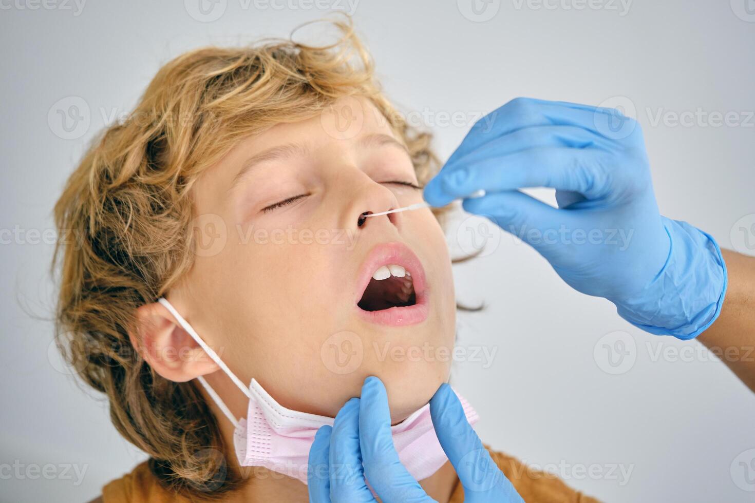 Crop medic taking coronavirus test from boy in hospital photo