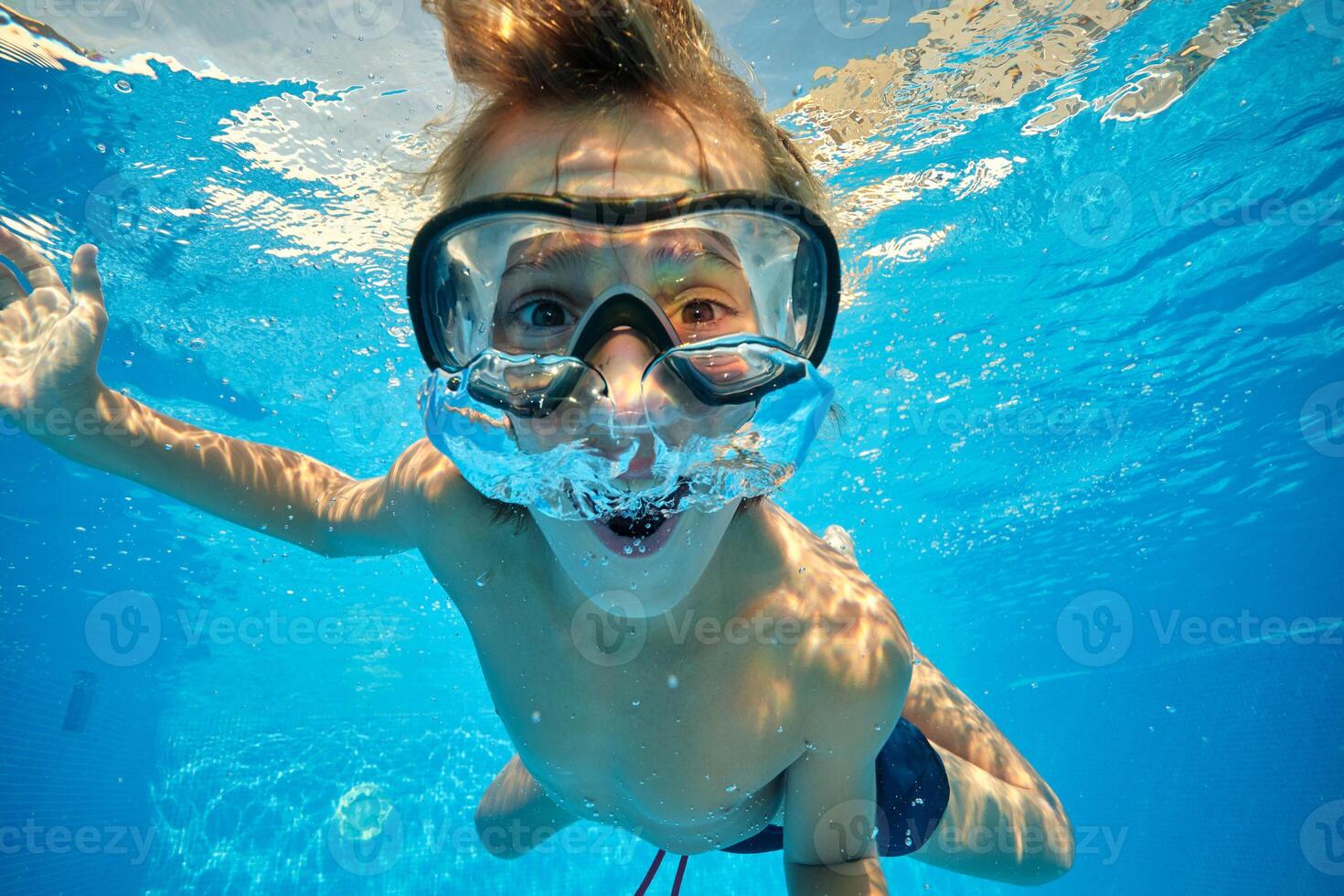 Amazed boy blowing air bubbles in pool photo