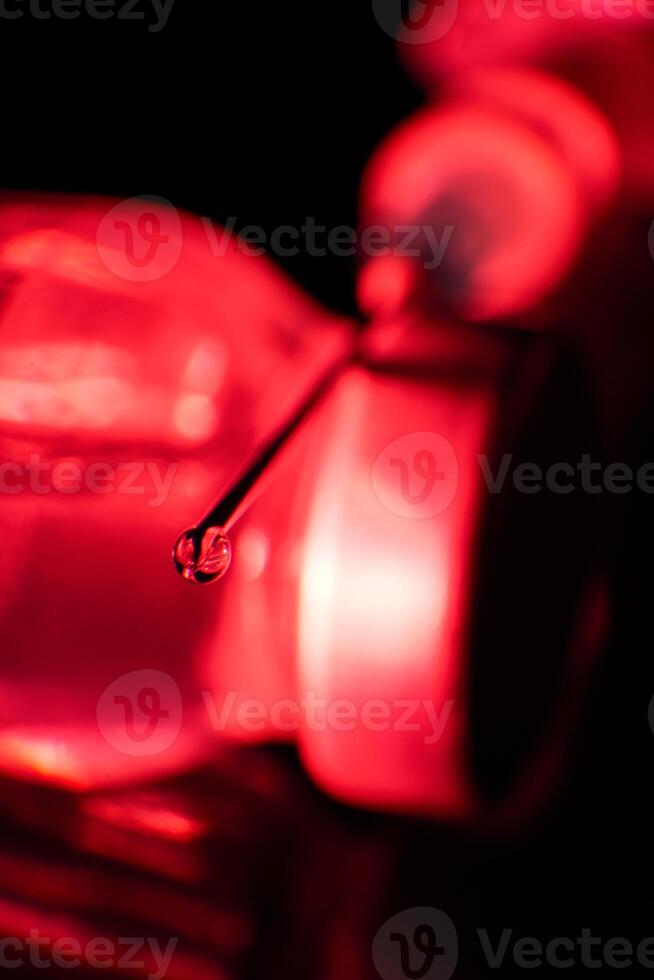 Hypodermic syringe needle with droplet of liquid on tip photo