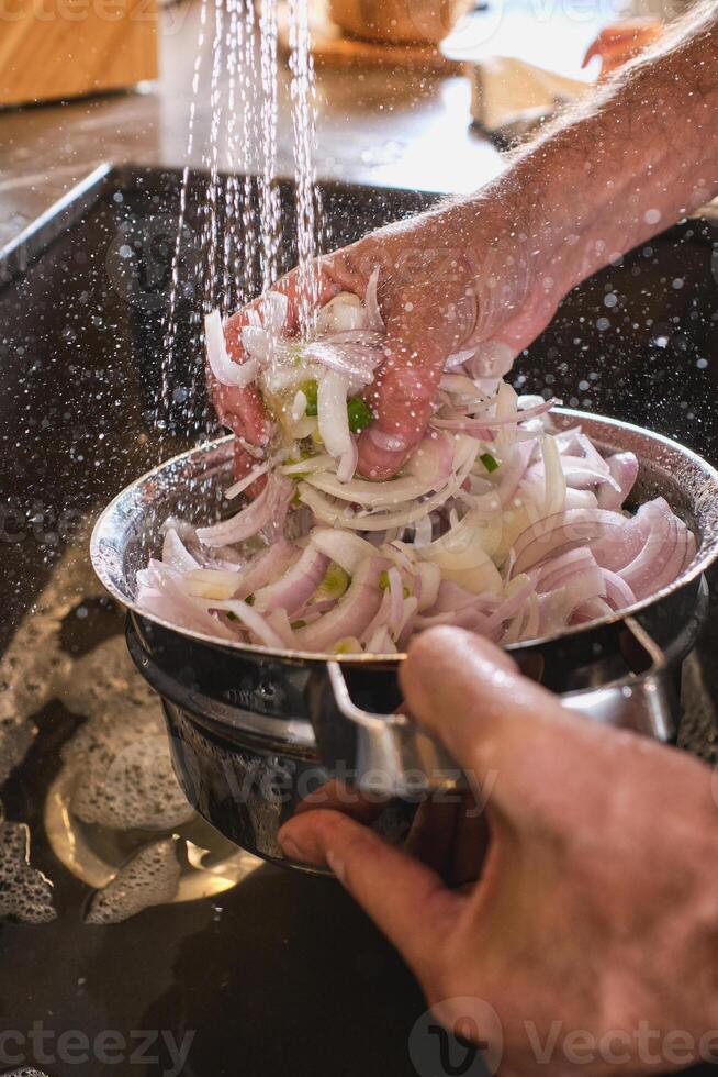Unrecognizable person rinsing onion under water photo