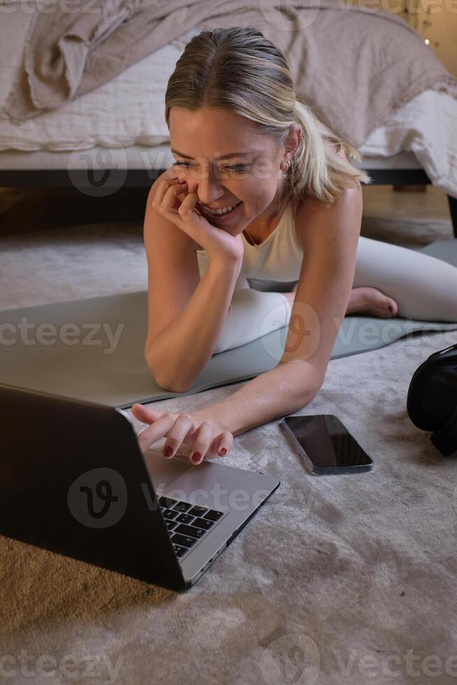 Cheerful woman using laptop before online yoga lesson photo