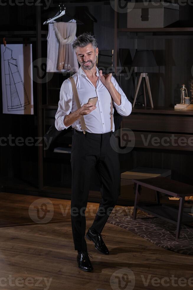 Mature man in elegant suit texting message on smartphone in ward photo