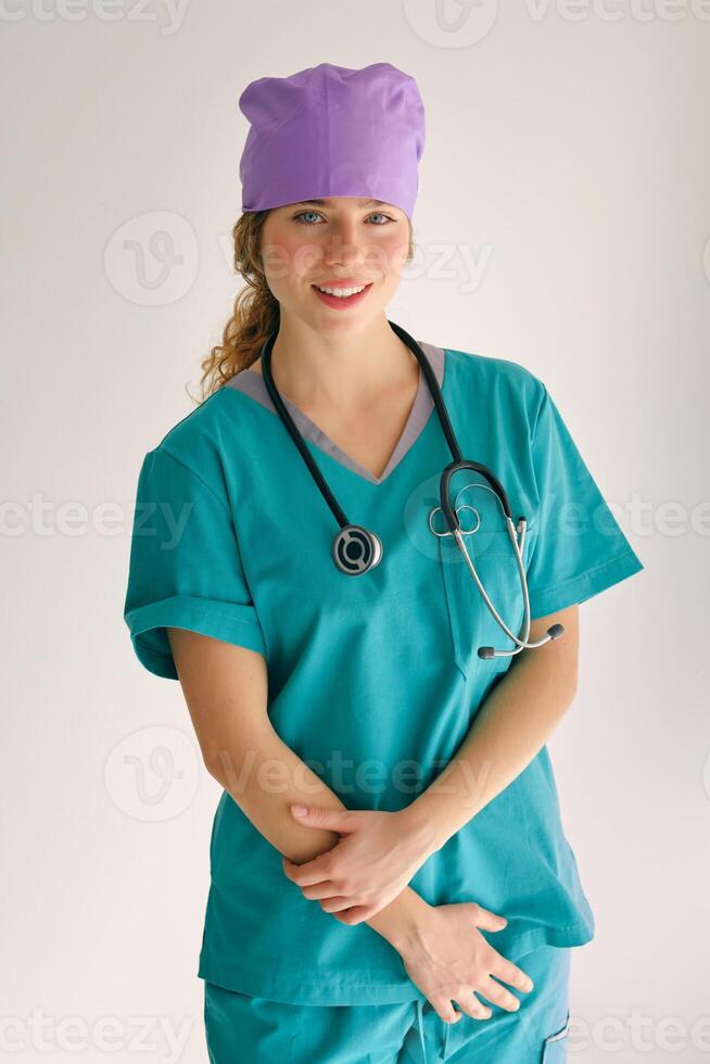 Glad female doctor in cap and uniform on gray background photo